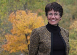 Image of Emmaus CEO Karen Jacobsen in front of fall leaves.