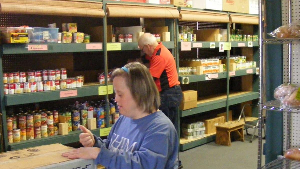 Image of Emmaus resident Marisa stocking shelves at a food pantry.