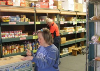 Image of Emmaus resident Marisa stocking shelves at a food pantry.