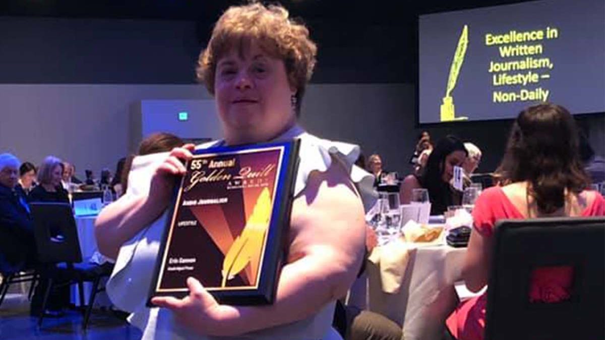 Image of Emmaus resident Erin Gannon holding up Golden Quill award at reception.