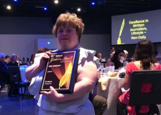 Image of Emmaus resident Erin Gannon holding up Golden Quill award at reception.