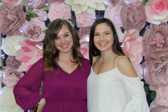 Image of two Purse bash guests in front of flower background.